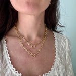 Close-up of a person wearing gold necklaces with a light background