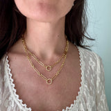 Close-up of a person wearing gold necklaces with a light background
