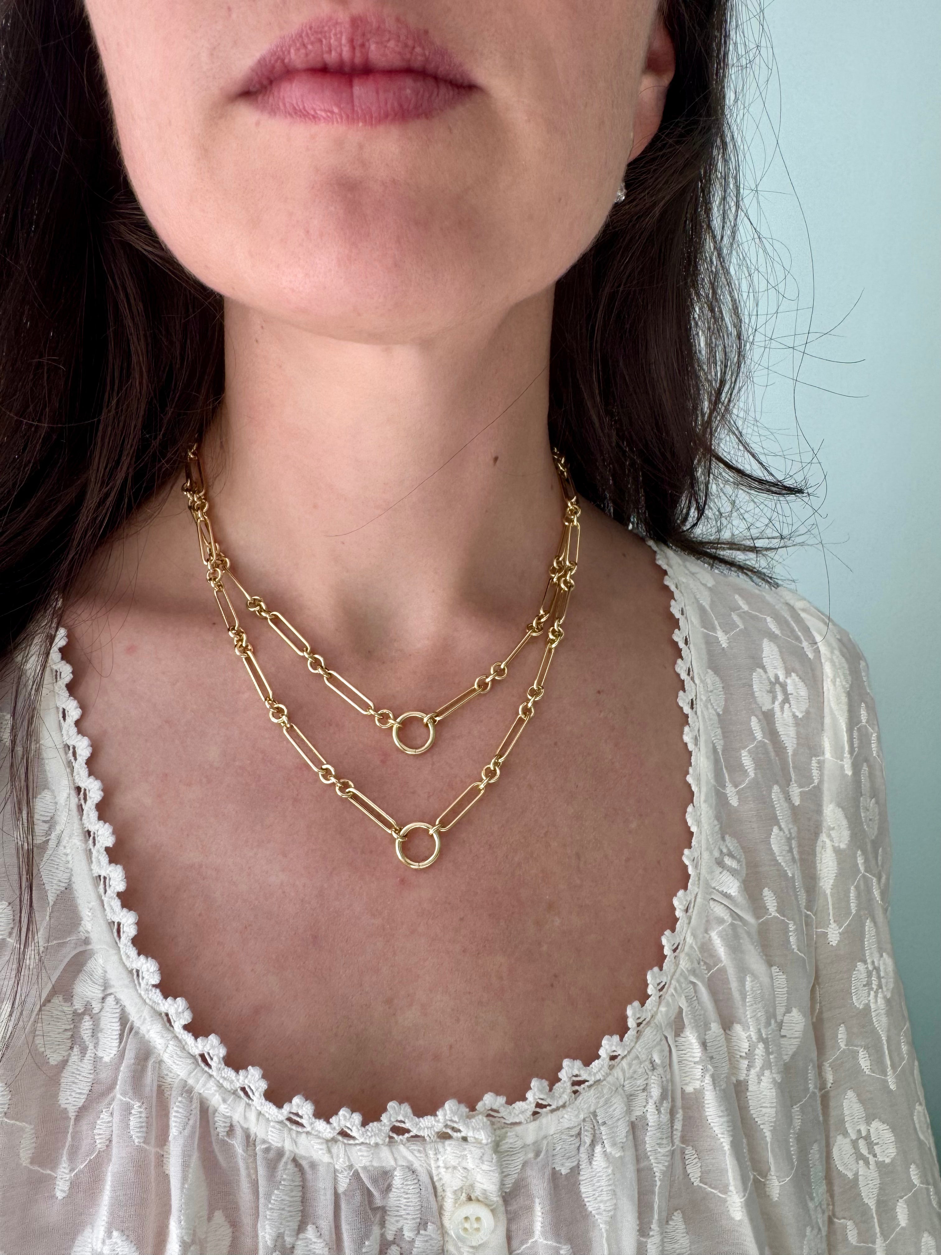 Close-up of a person wearing gold necklaces with a light background