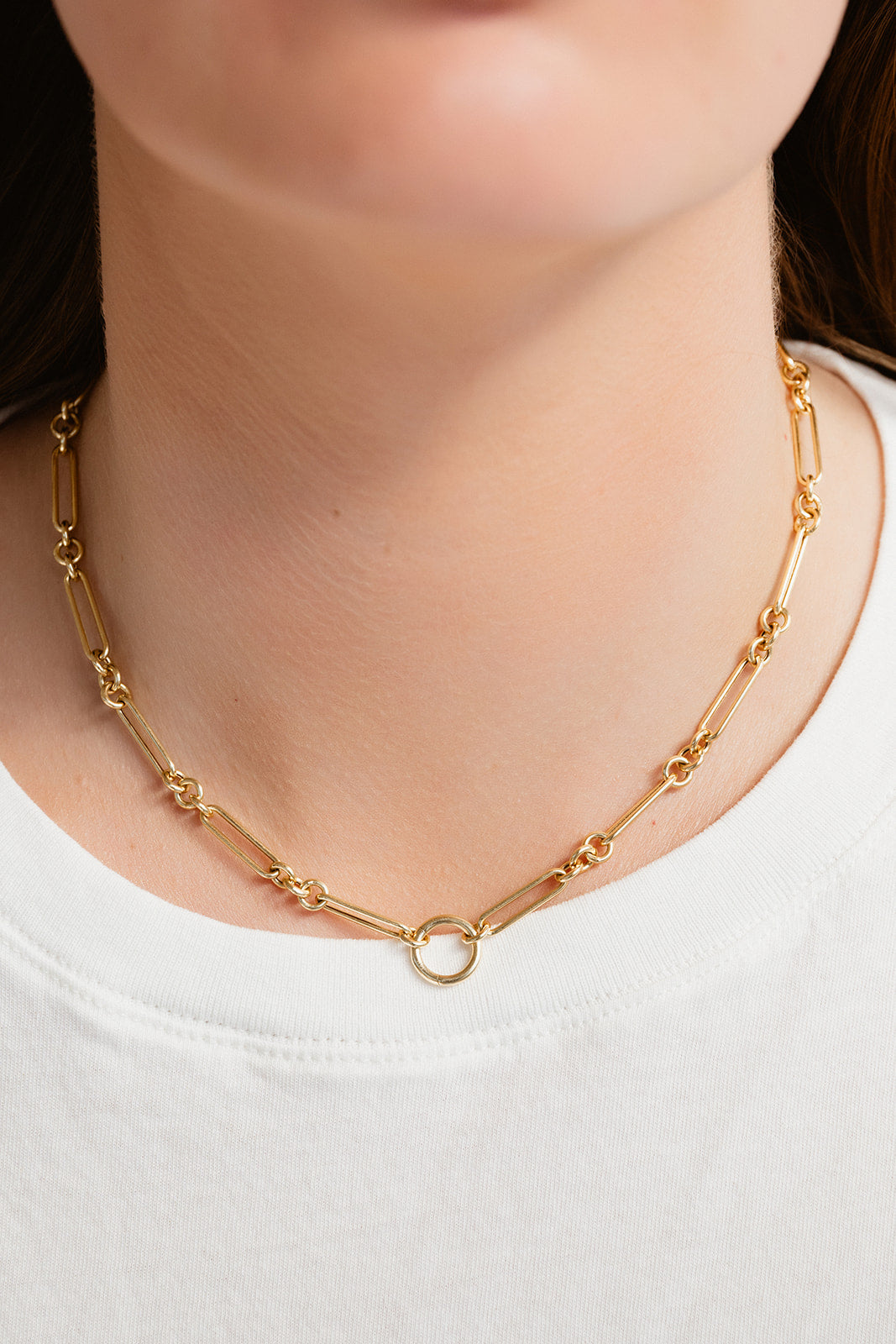Gold chain necklace worn by a person on a white background