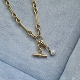 Gold necklace with a pendant on a textured blue surface