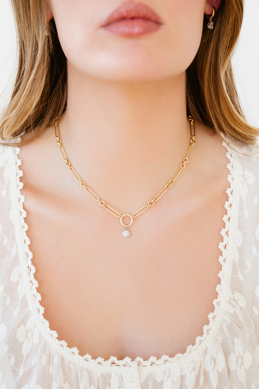 Gold necklace with a diamond pendant worn by a person against a white background