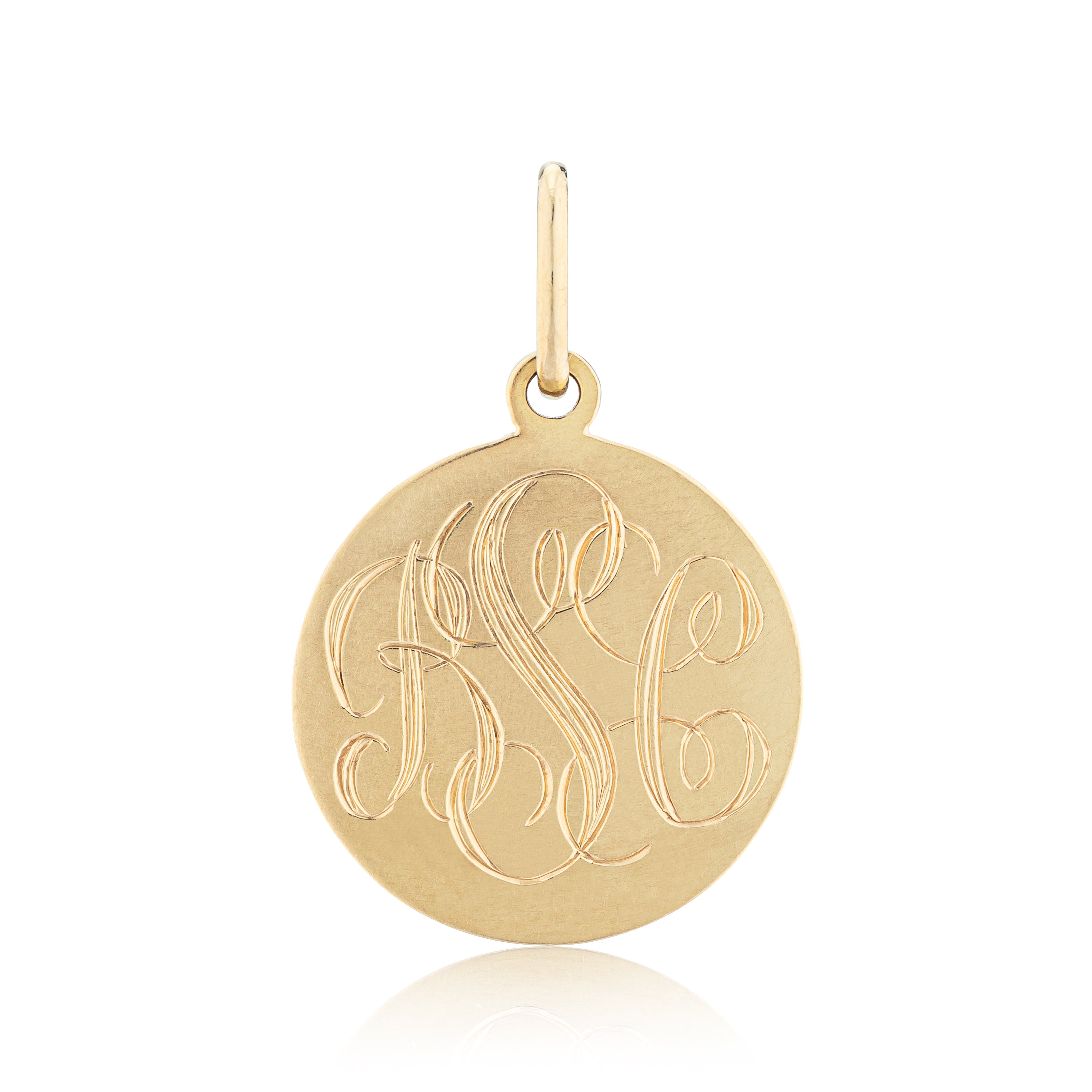 Gold pendant with engraved initials on a white background