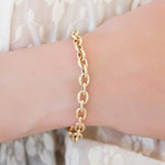 Gold chain bracelet on a wrist with a light background