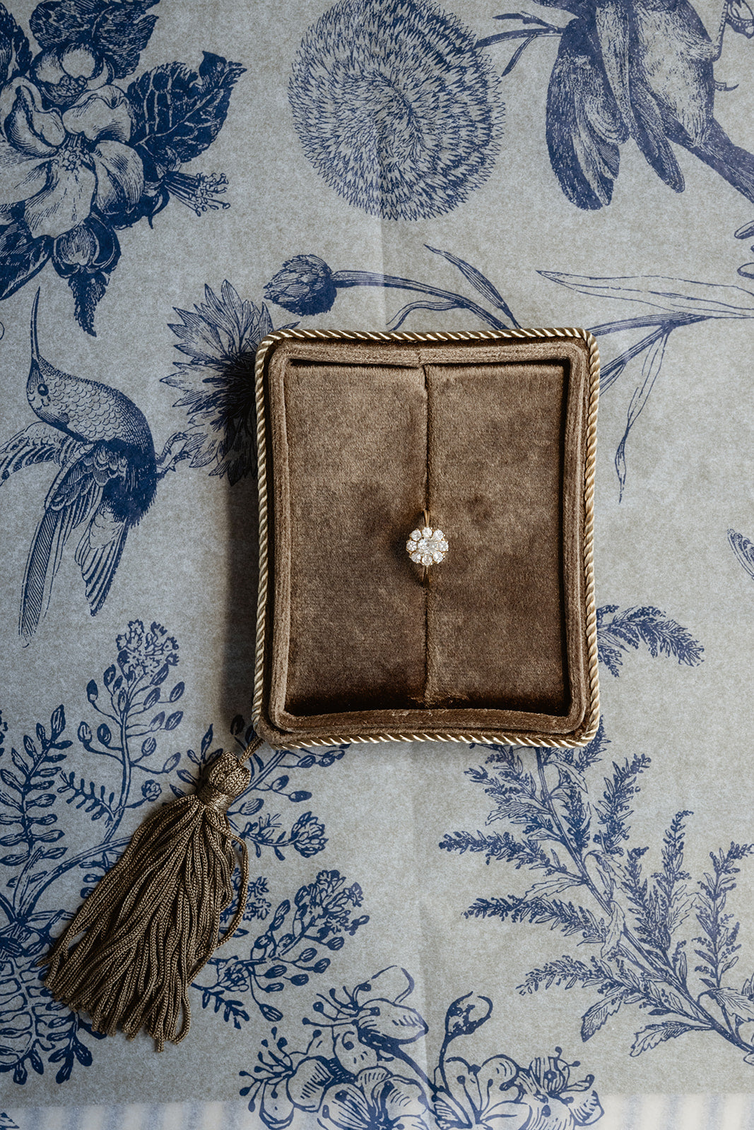Ring in a brown box on a floral-patterned fabric background