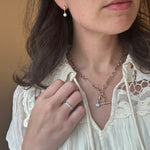 Close-up of a woman wearing a gold necklace and ring, with a focus on jewelry details.