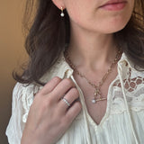 Close-up of a woman wearing a gold necklace and ring, with a focus on jewelry details.