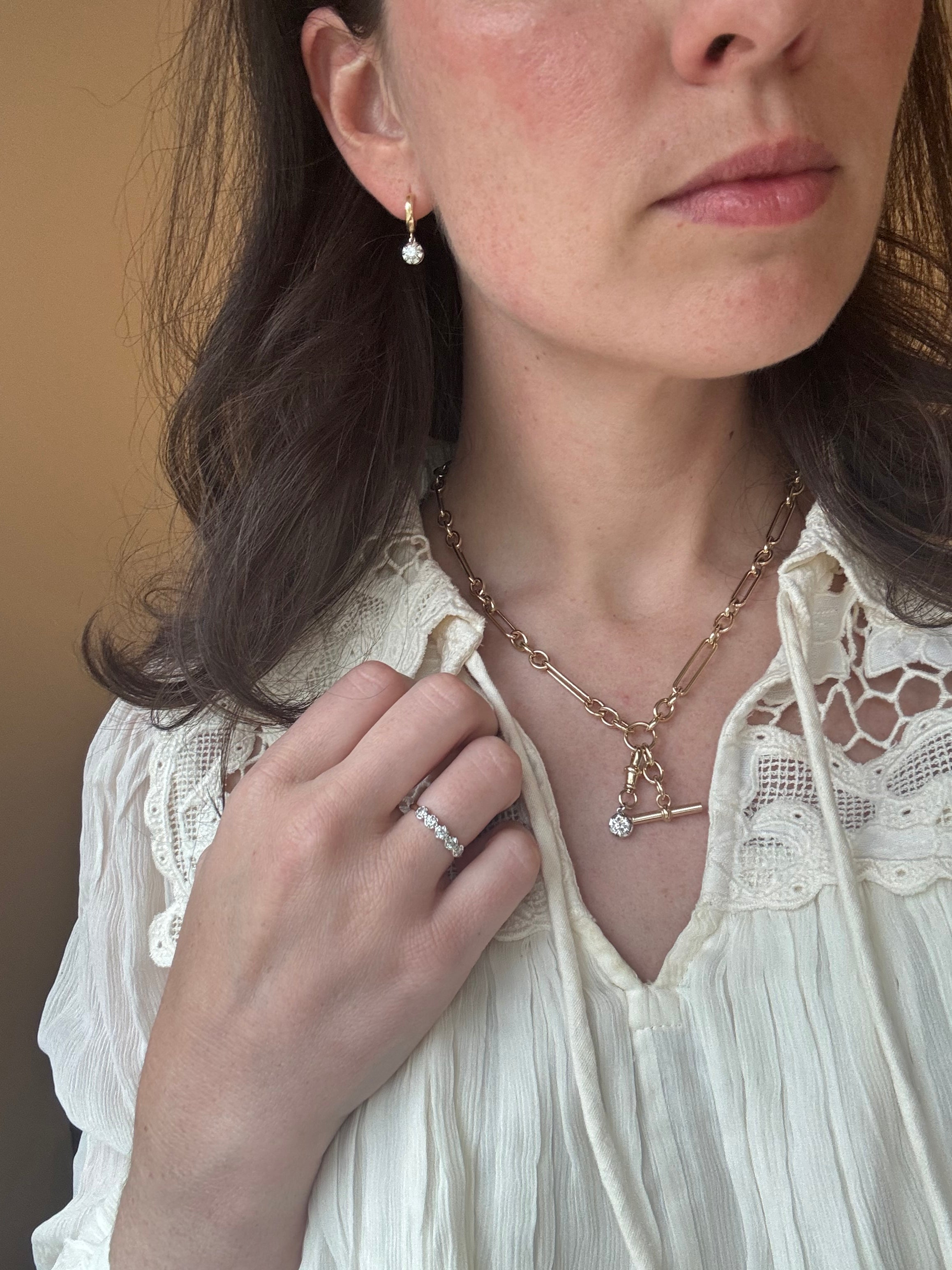 Close-up of a woman wearing a gold necklace and ring, with a focus on jewelry details.