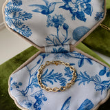 Gold bracelet on a blue floral fabric jewelry box