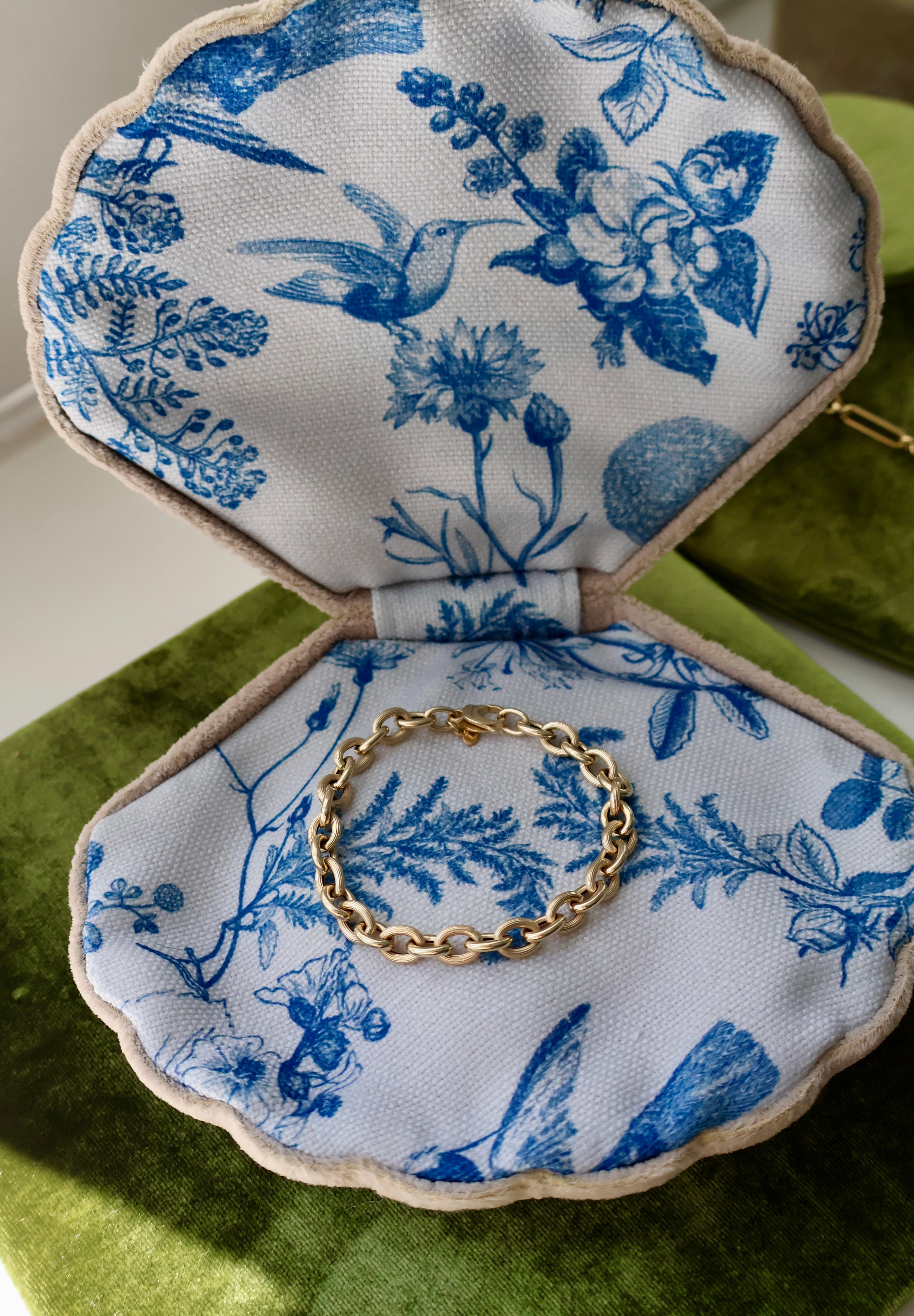 Gold bracelet on a blue floral fabric jewelry box