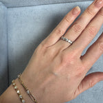 Hand wearing a diamond ring and bracelet on a light blue cushion