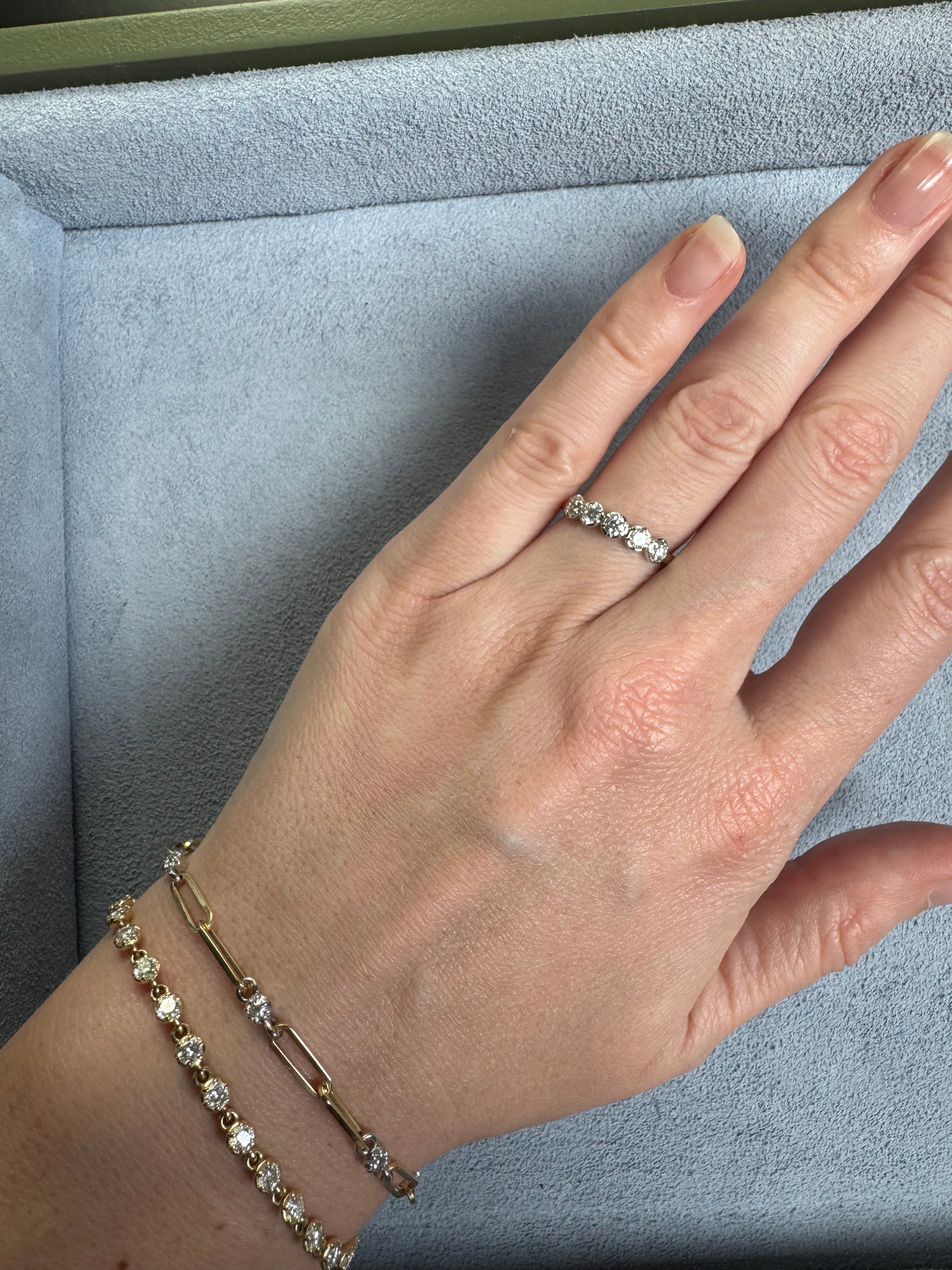 Hand wearing a diamond ring and bracelet on a light blue cushion