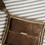 Brown suede clutch with tassel on a striped fabric background