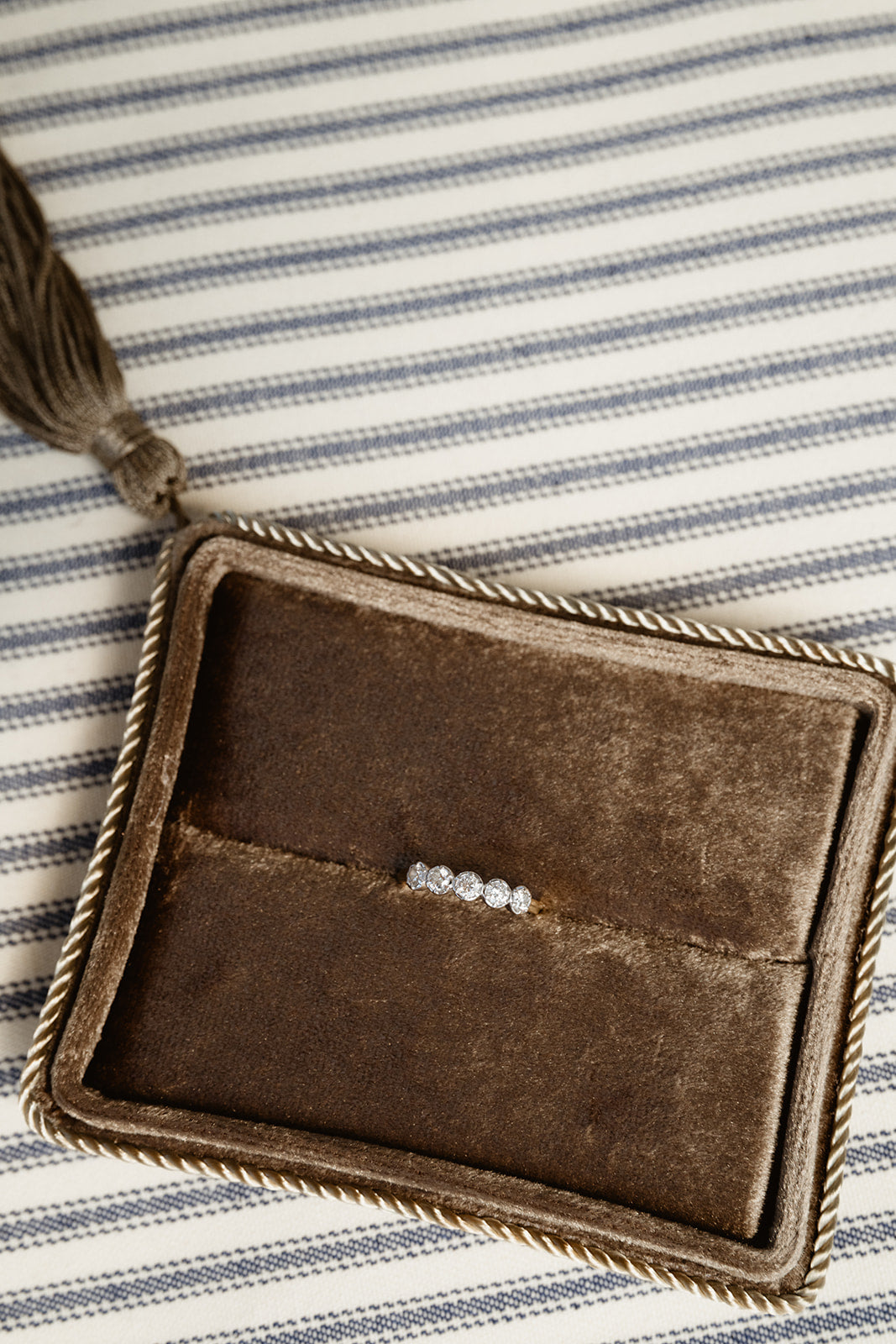 Brown suede clutch with tassel on a striped fabric background