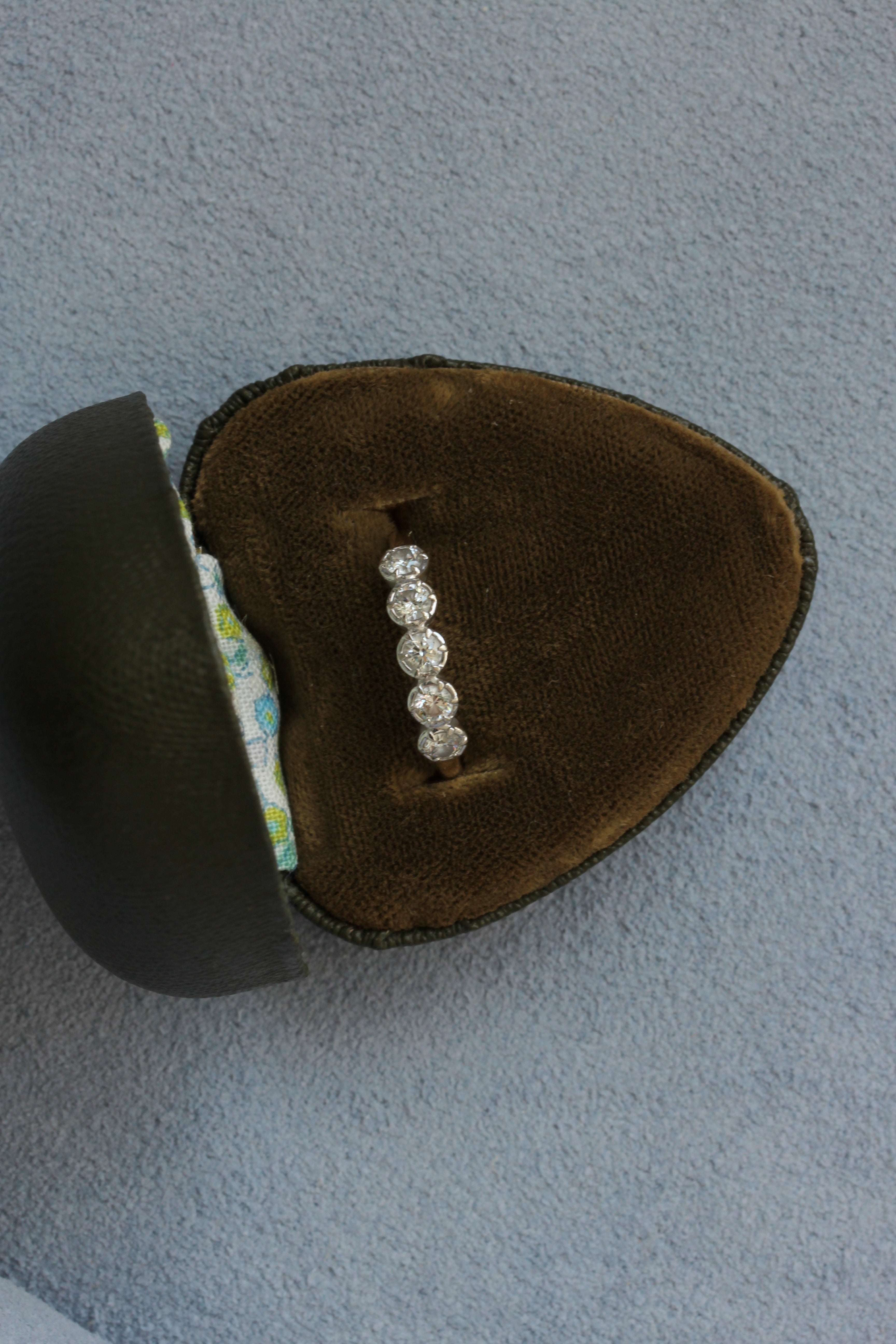 Diamond ring in a brown velvet box on a gray background