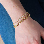 Close-up of a hand wearing gold bracelets on a blurred background