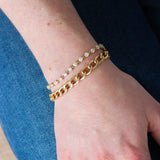 Close-up of a hand wearing gold bracelets on a blurred background