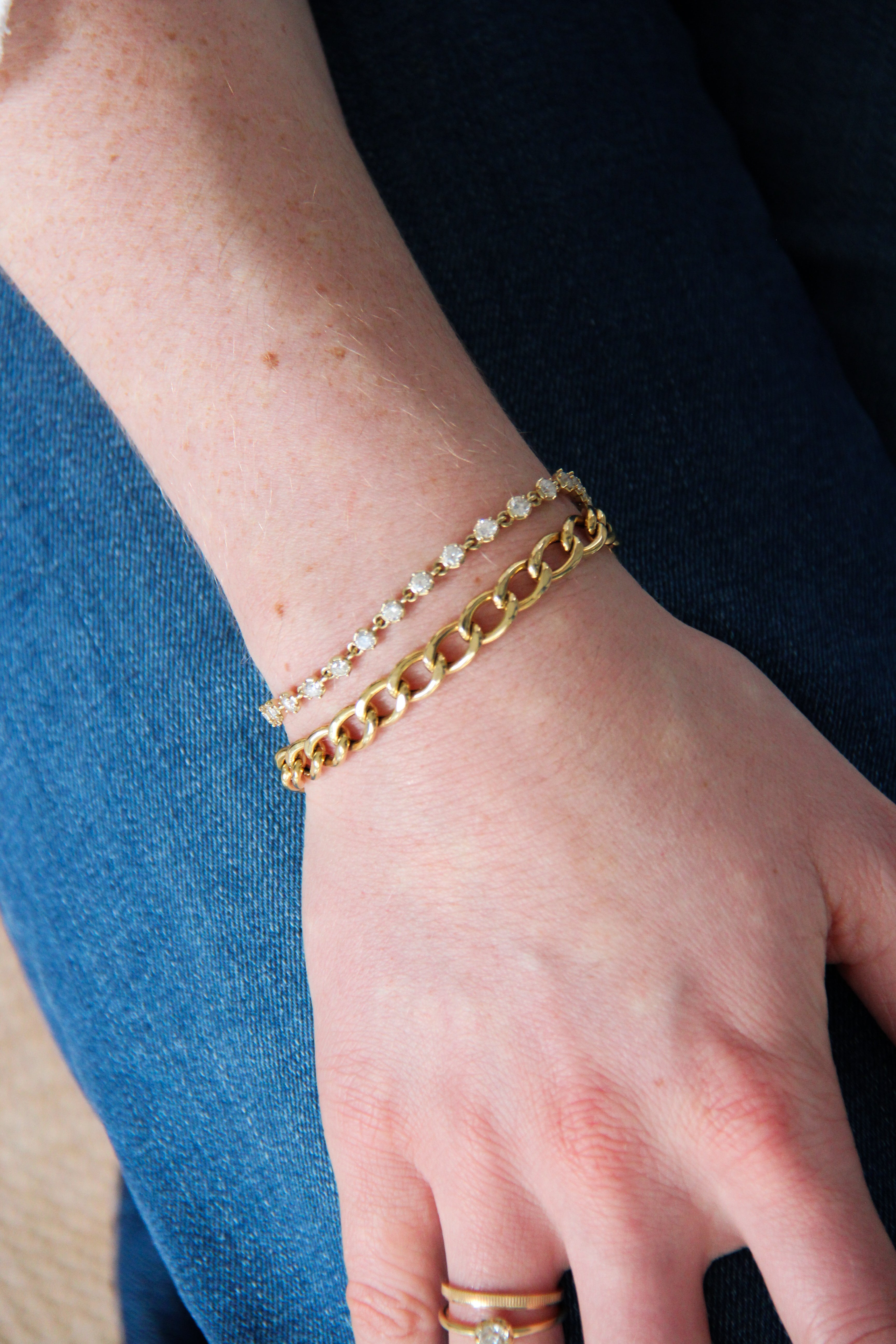 Close-up of a hand wearing gold bracelets on a blurred background