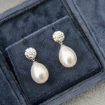 Pearl earrings with silver tops in a blue jewelry box