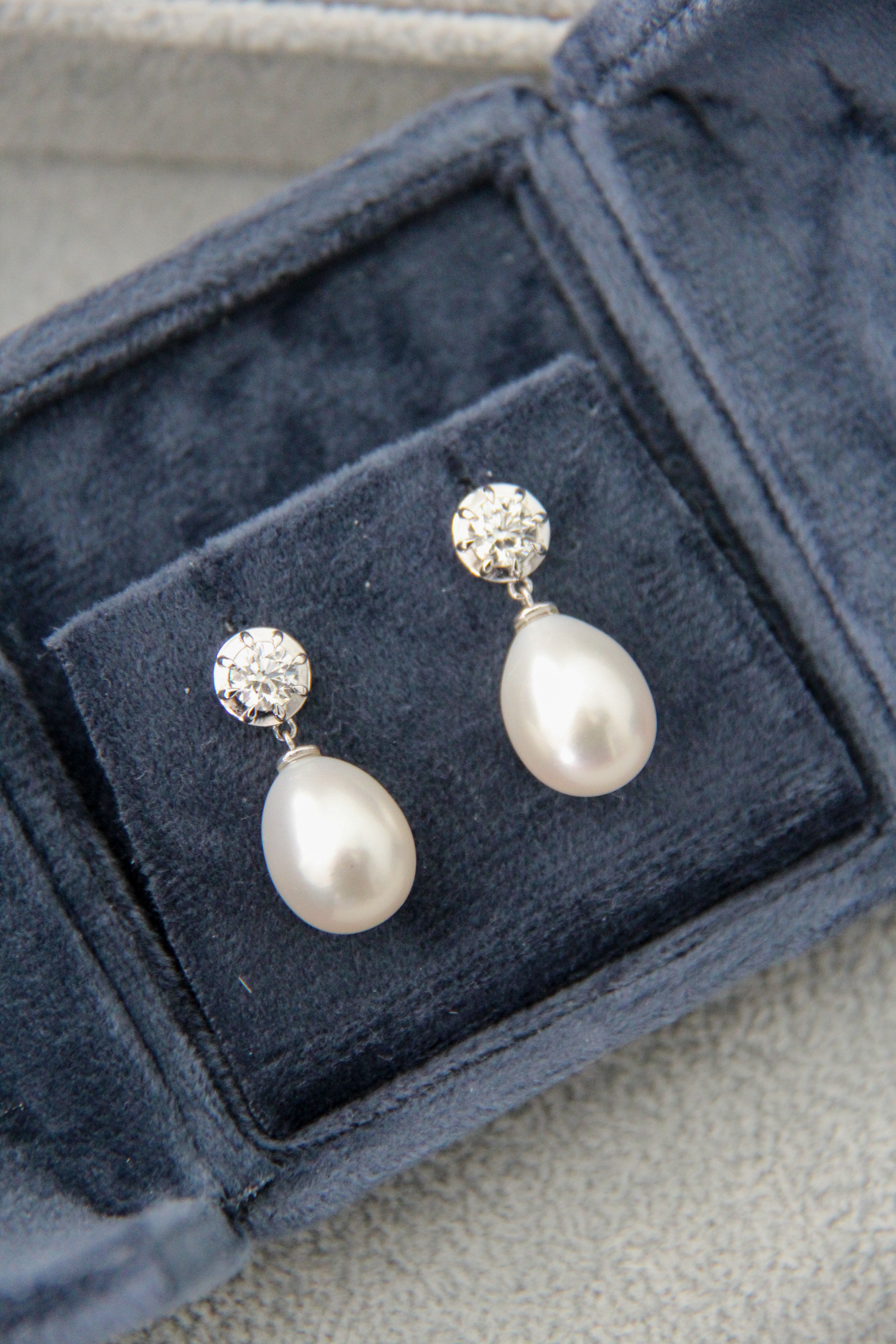 Pearl earrings with silver tops in a blue jewelry box