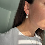 Close-up of a person wearing pearl earrings with a blurred background
