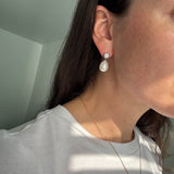 Close-up of a person wearing pearl earrings with a blurred background