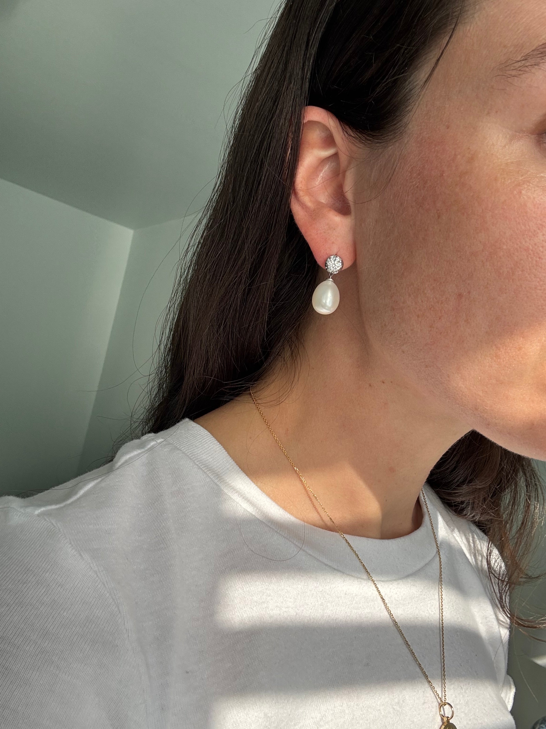 Close-up of a person wearing pearl earrings with a blurred background