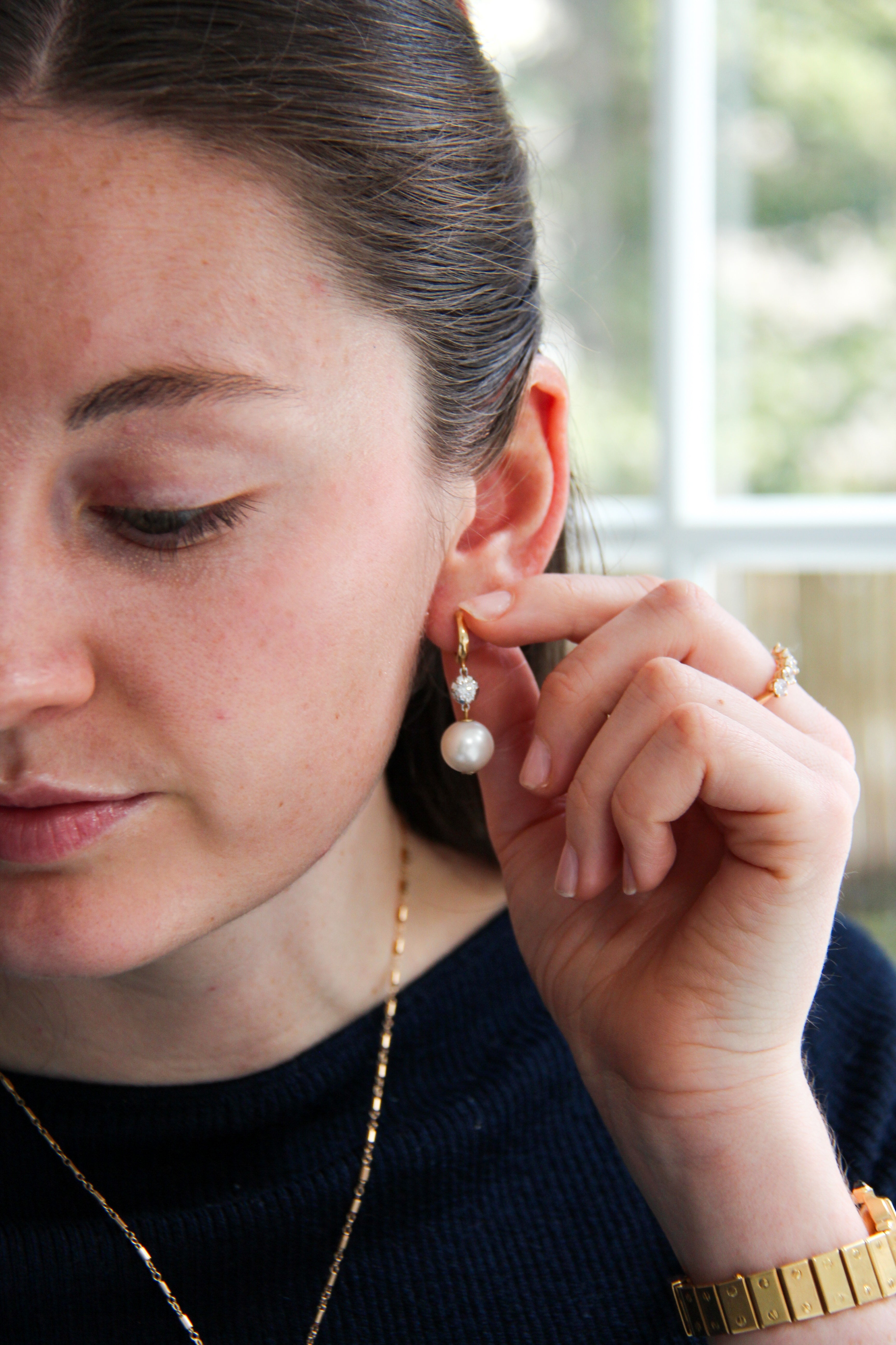 Woman adjusting a pearl earring with a blurred background