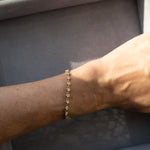 Gold bracelet on a wrist with a neutral background