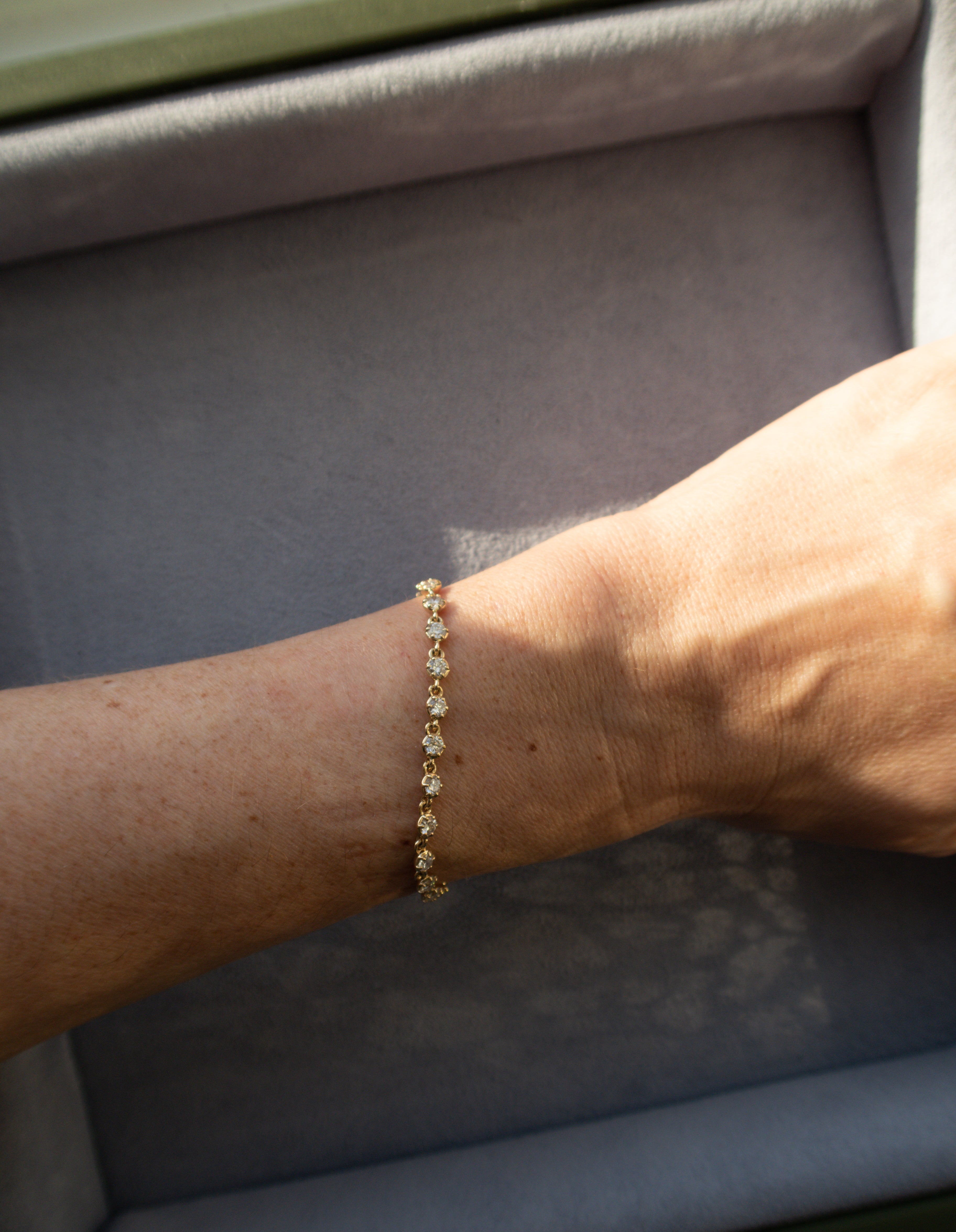 Gold bracelet on a wrist with a neutral background