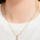 Gold necklace with a diamond pendant on a white background