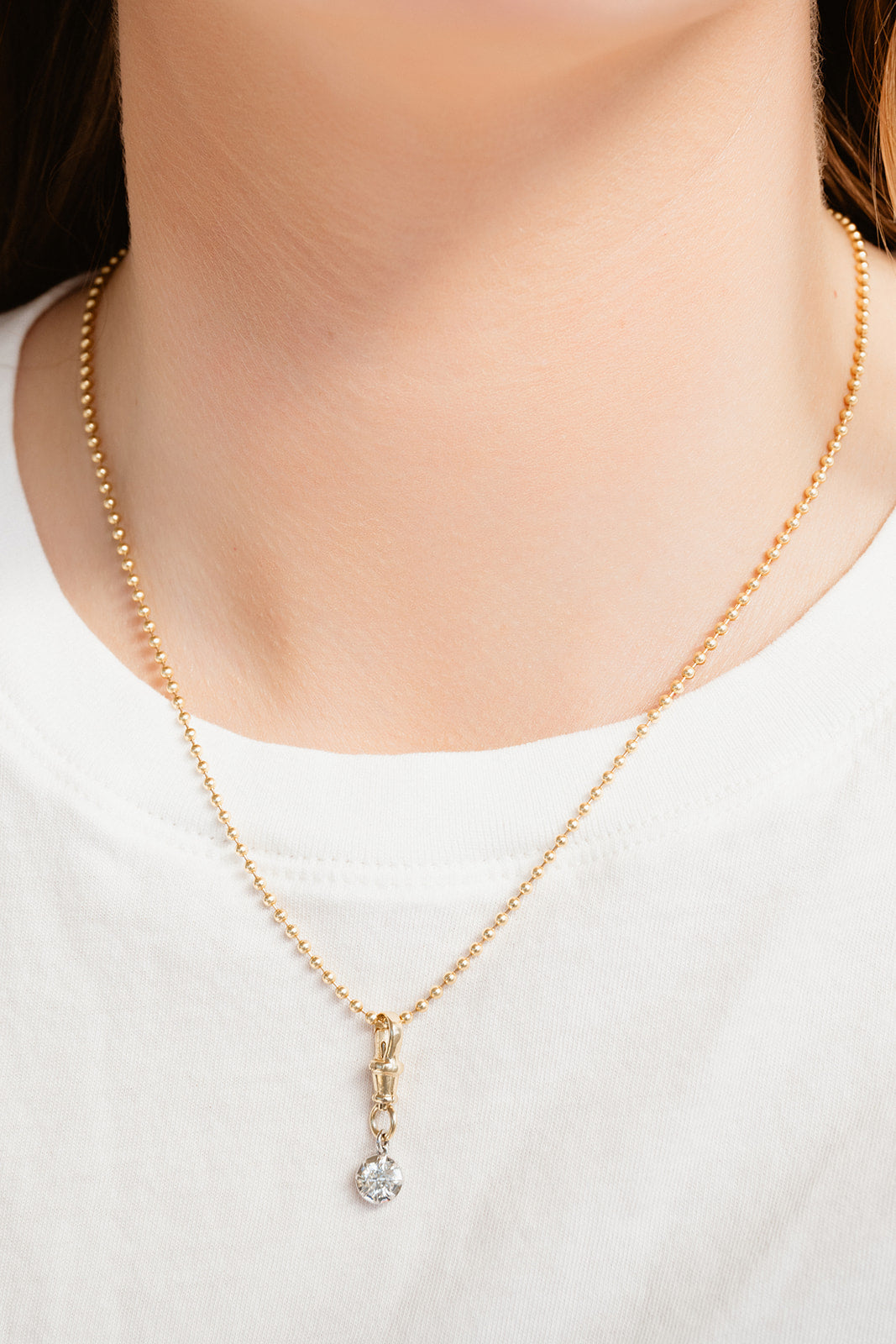 Gold necklace with a diamond pendant on a white background