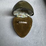 Diamond ring in an open brown jewelry box on a gray surface
