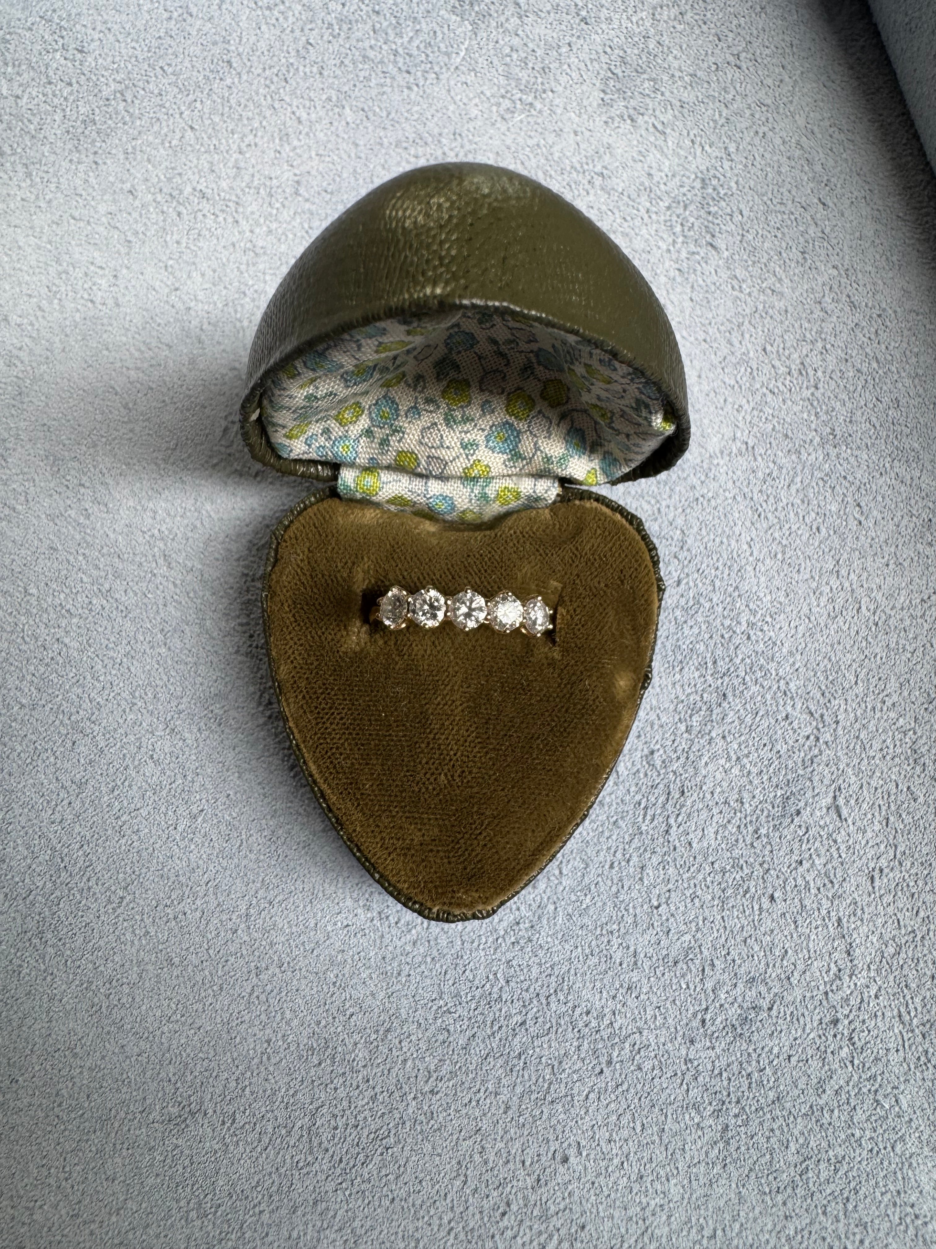 Diamond ring in an open brown jewelry box on a gray surface