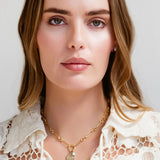 Woman wearing a gold necklace with a plain background