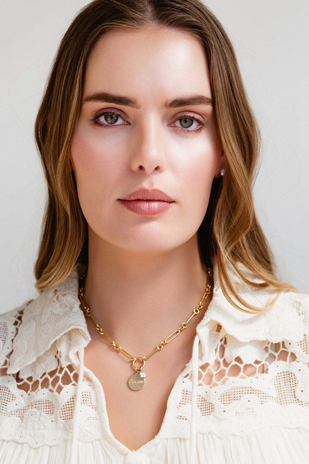 Woman wearing a gold necklace with a plain background