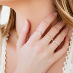 Close-up of a person wearing gold necklaces and rings on a blurred background