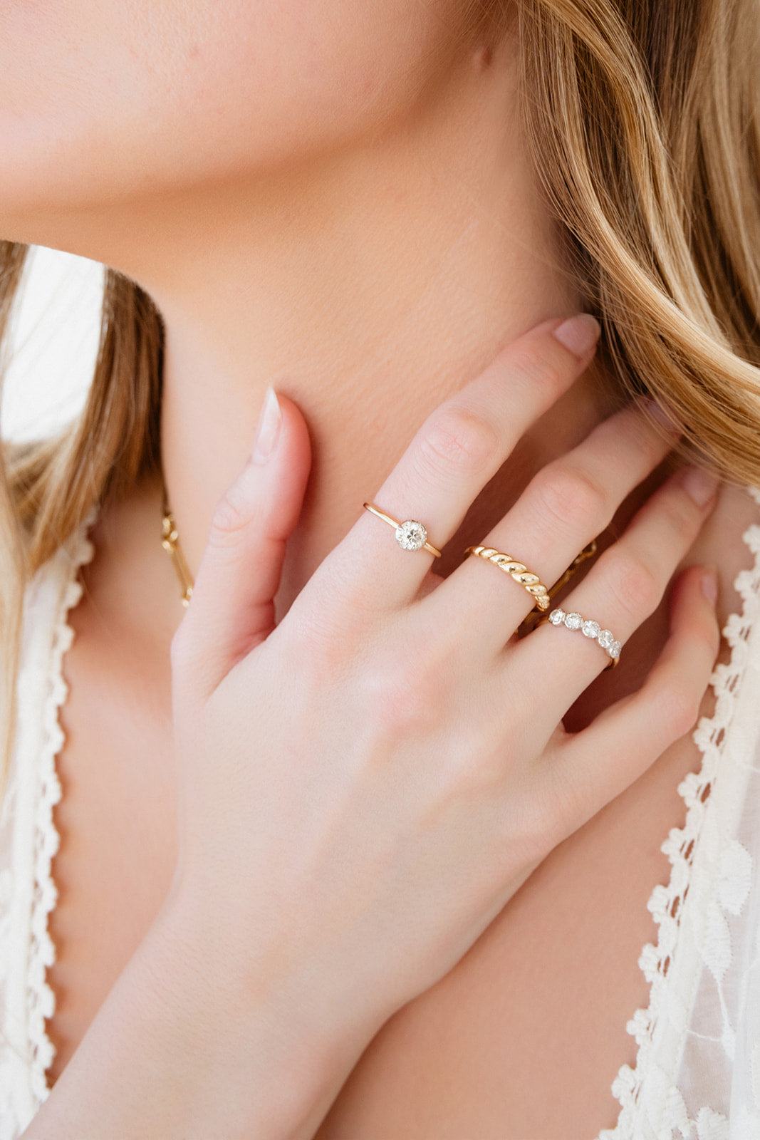 Close-up of a person wearing gold necklaces and rings on a blurred background